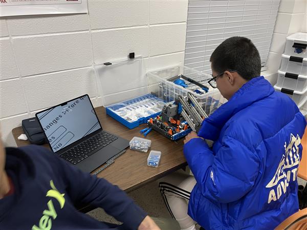 A student sits and works on a robot.